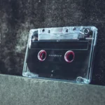 A clear cassette tape resting on a concrete surface evokes a vintage and nostalgic vibe.