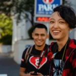 Two friends smiling while enjoying a sunny day on the street, capturing joy and friendship.