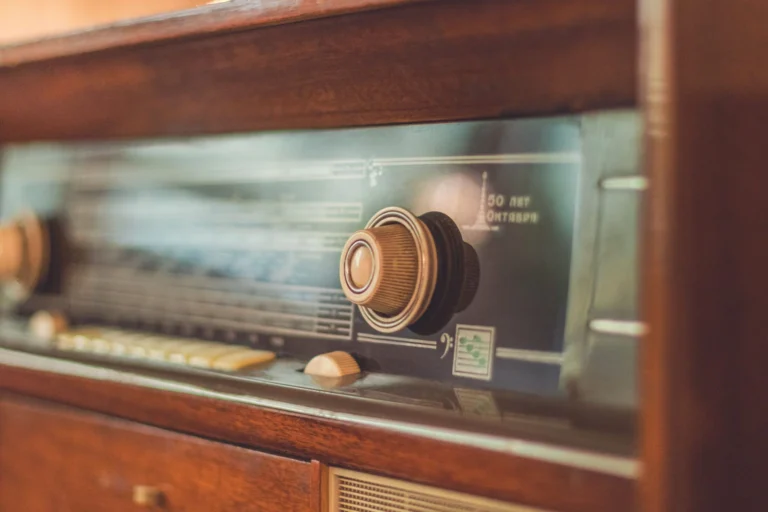 Close-up of a vintage radio showcasing its knobs and dial, reflecting retro style.