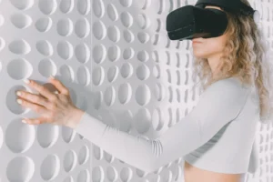 Woman explores a white textured wall using virtual reality headset, capturing advanced tech and tactile perception.