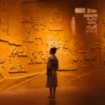 Back view of anonymous female traveler standing near ancient wall with Egyptian engraving
