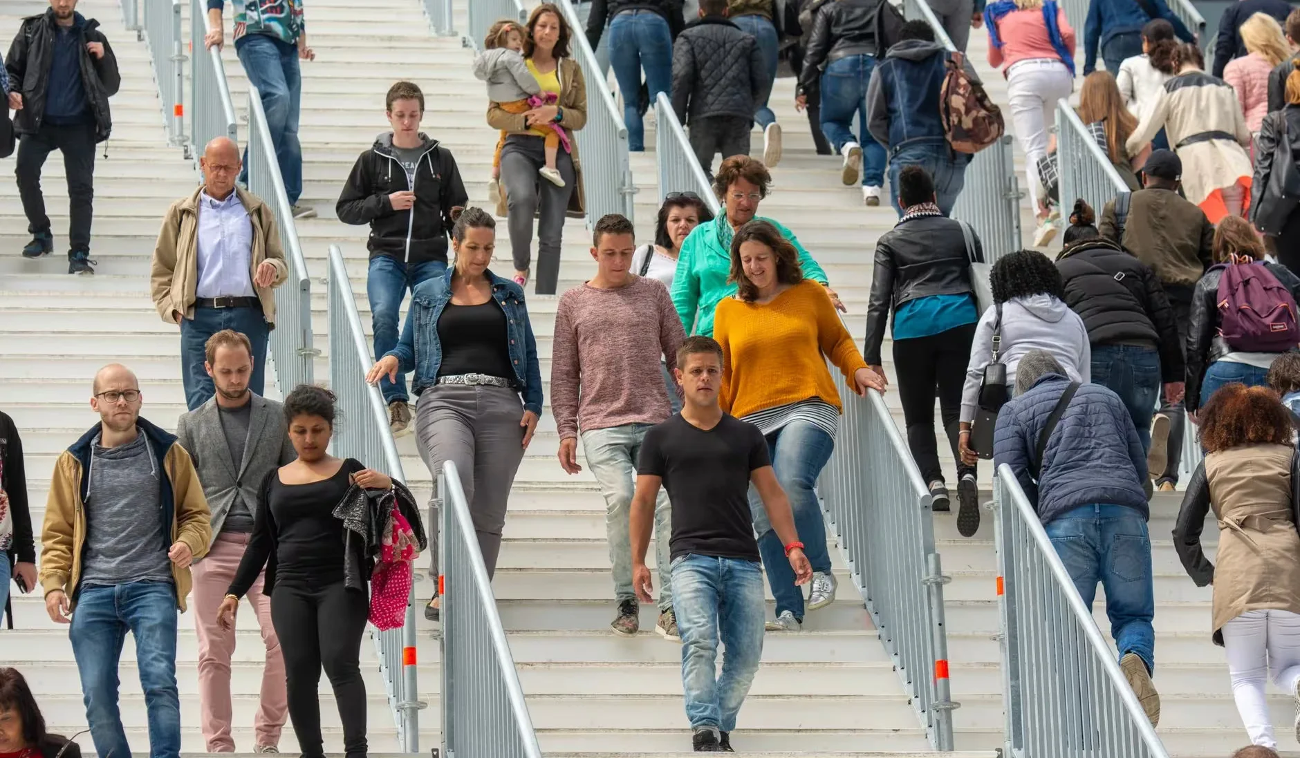 A diverse crowd of people walking downstairs in a bustling urban environment, showcasing everyday life.
