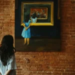 A woman admiring a painting in an art gallery, featuring a rustic brick wall.