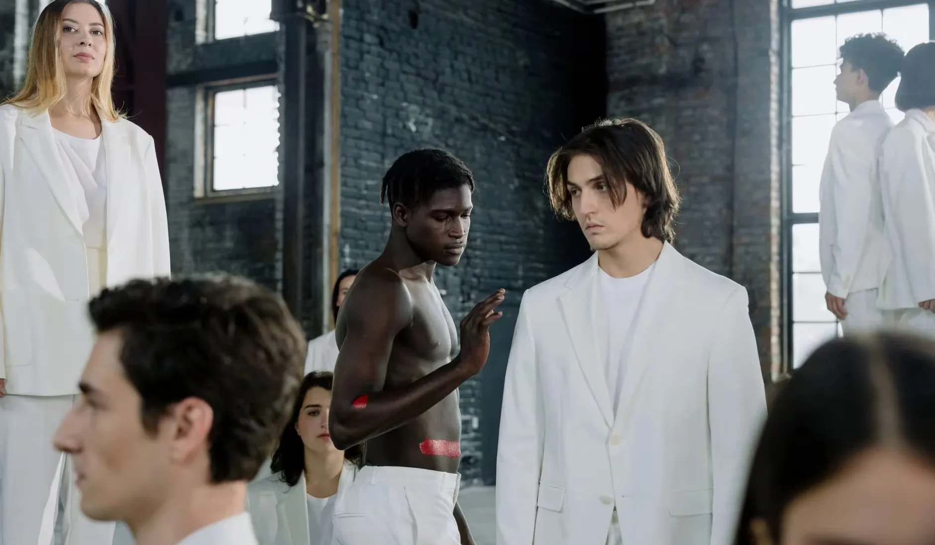 Models in a fashion shoot wearing white outfits in an industrial space.