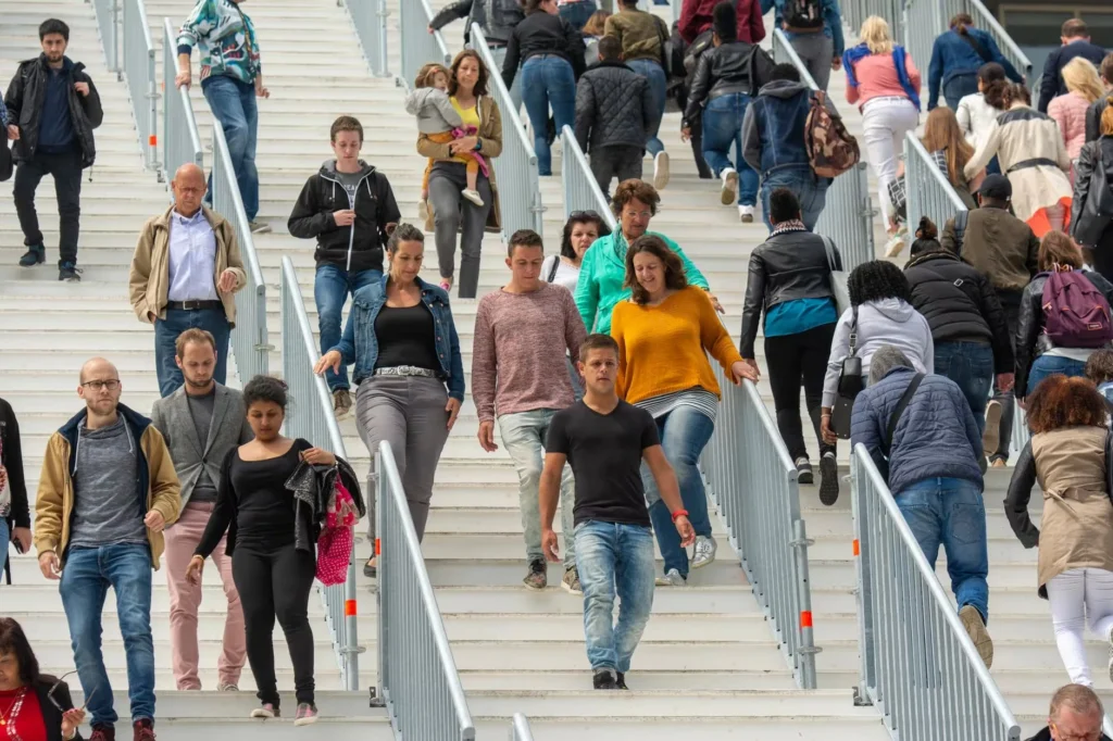 A diverse crowd of people walking downstairs in a bustling urban environment, showcasing everyday life.