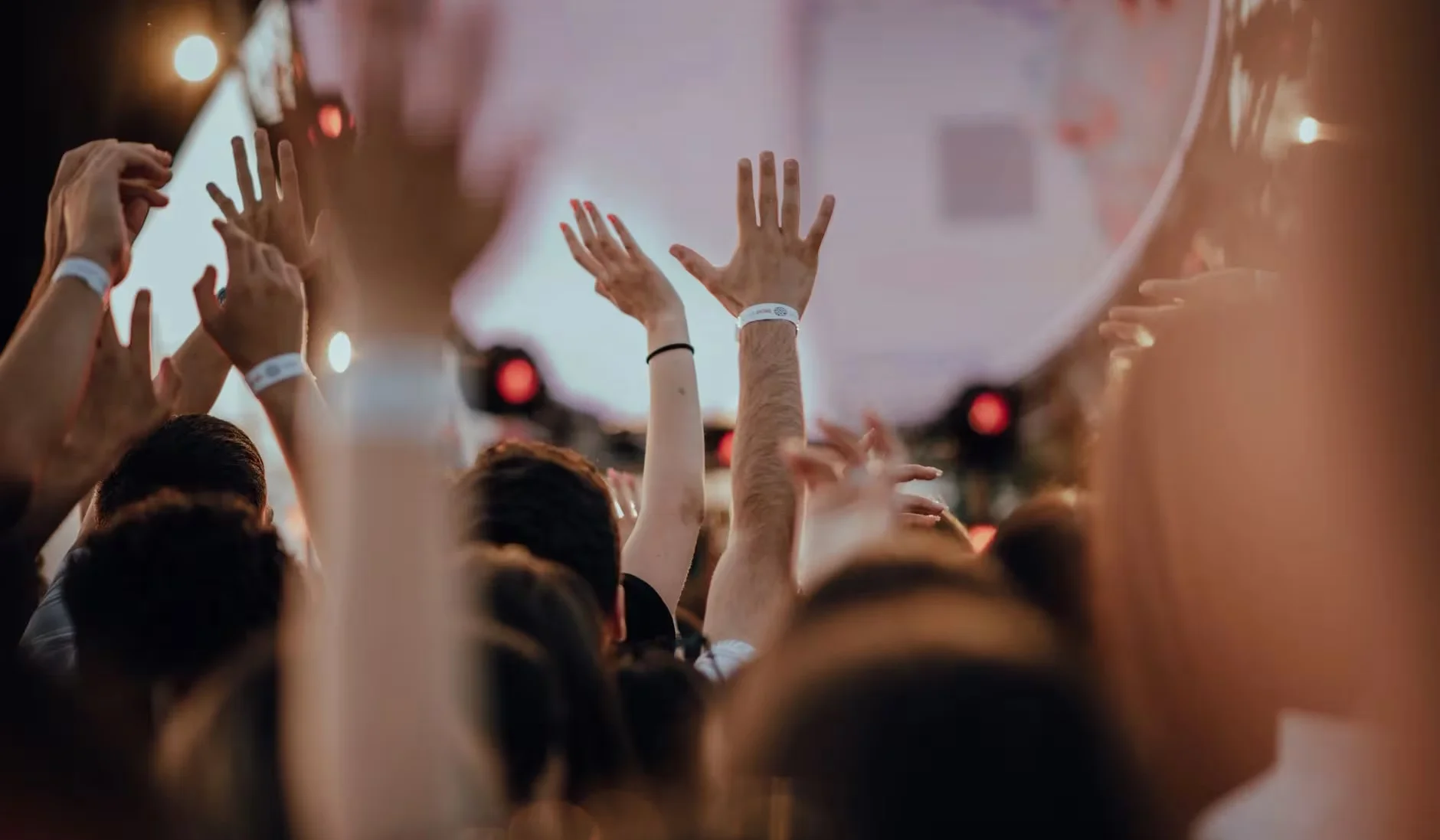 Vibrant scene of a thrilled audience with raised arms at an outdoor concert.
