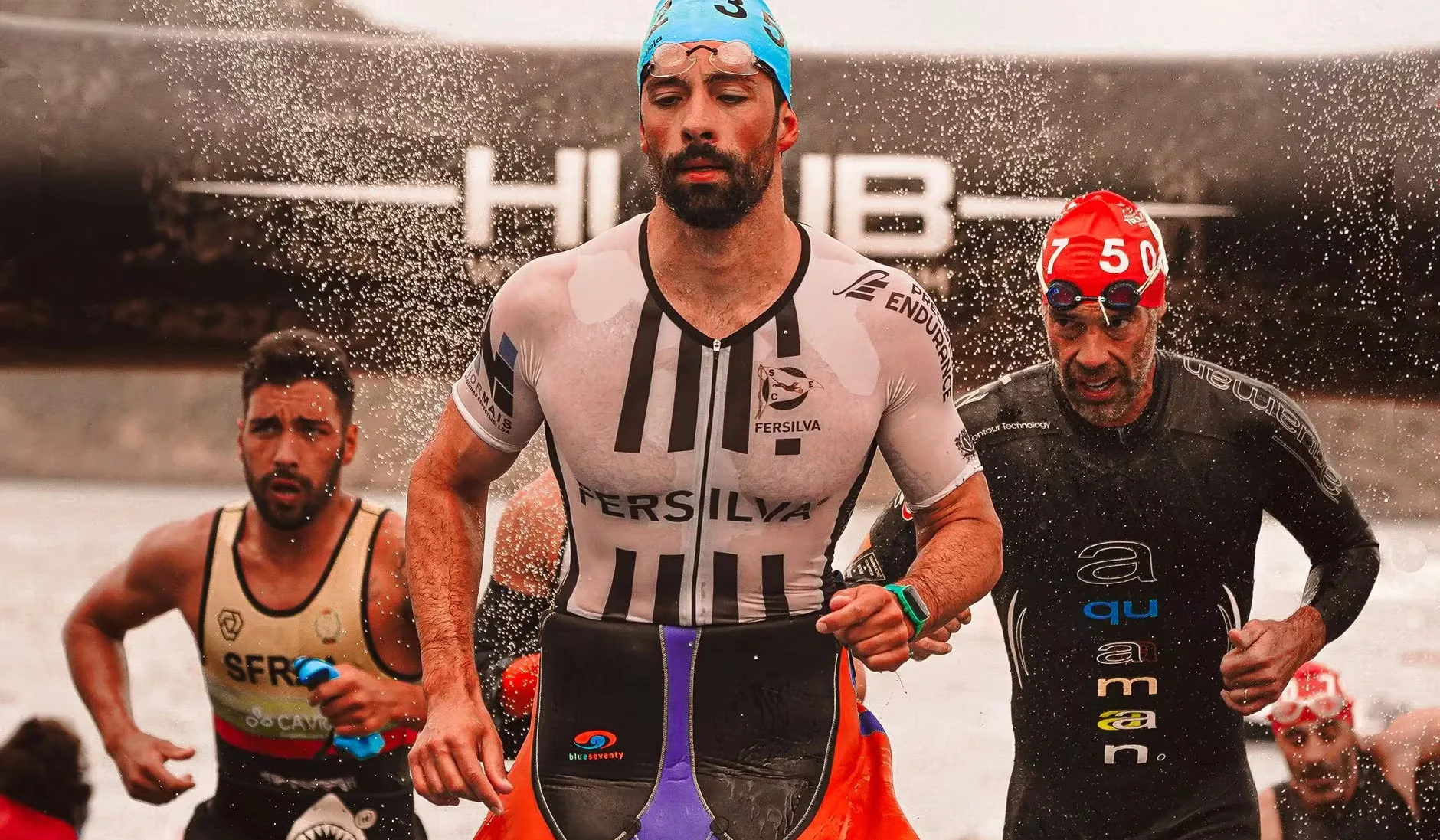 Runners sprinting through water during a competitive triathlon event outdoors.