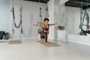 A woman in activewear practicing yoga indoors, demonstrating balance and flexibility with aerial equipment.