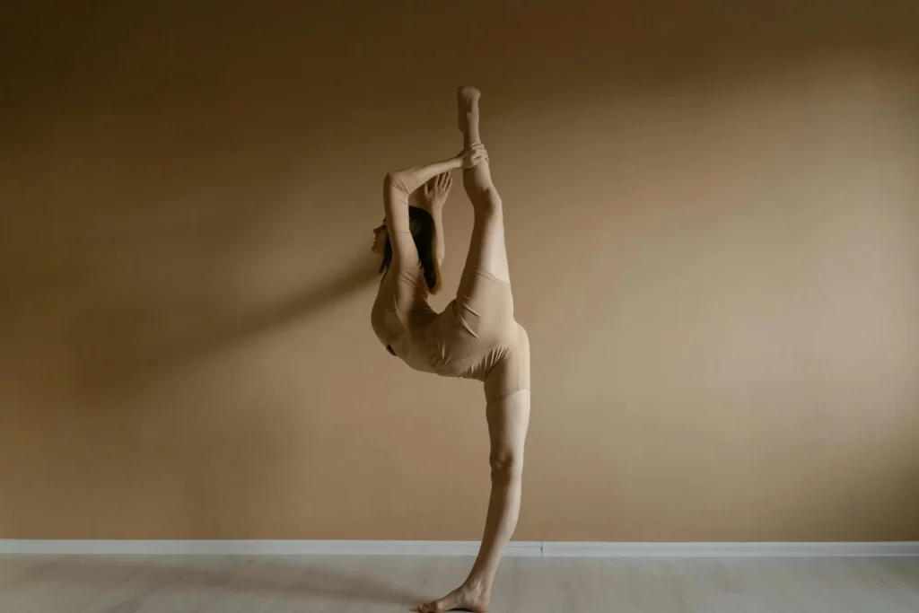 A graceful ballerina practicing an impressive ballet stretch indoors. Perfect for fitness and dance themes.