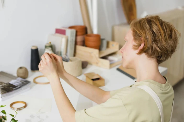 Caucasian woman crafting in a minimalist workspace with sewing supplies and plants.