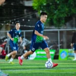 Dynamic action shot of a football player in full motion during a match in Hà Nội, Vietnam.