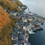 An aerial shot of Hallstatt, Austria surrounded by autumn foliage and lake views.