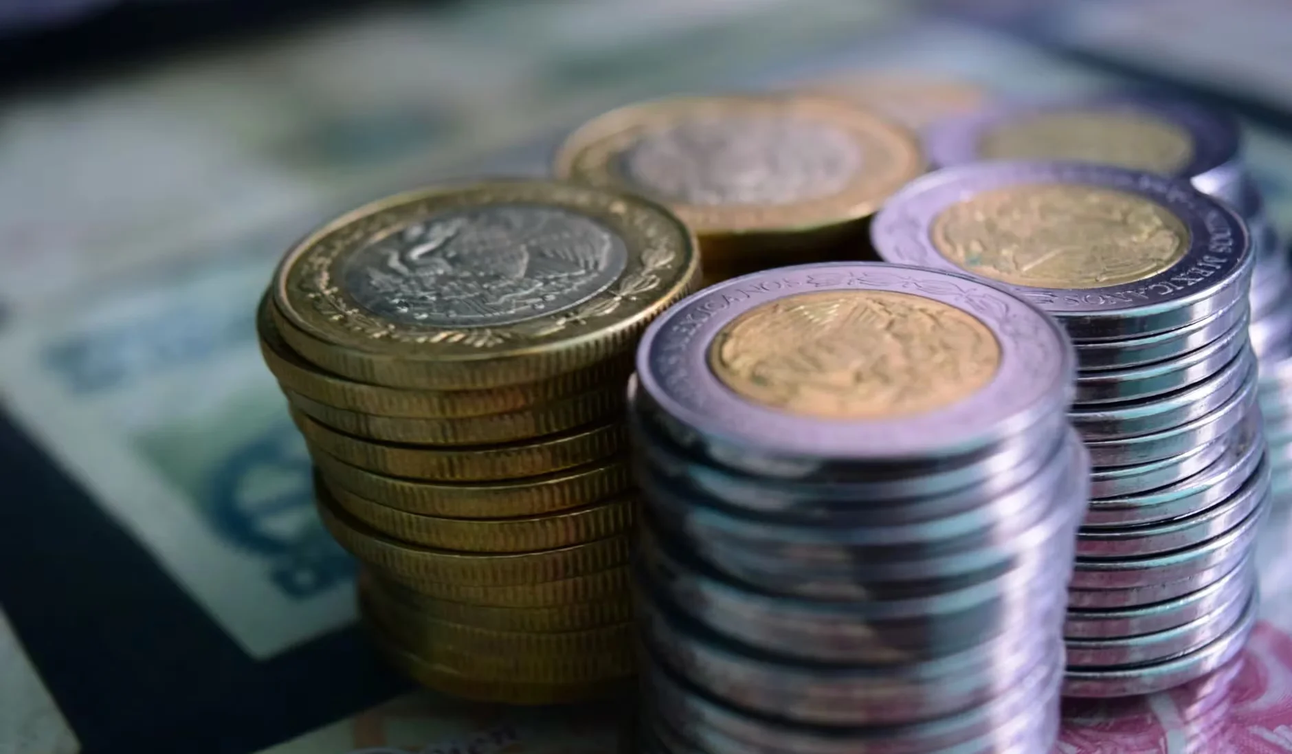 Close-up of stacked gold and silver coins on various currency notes, symbolizing wealth and savings.