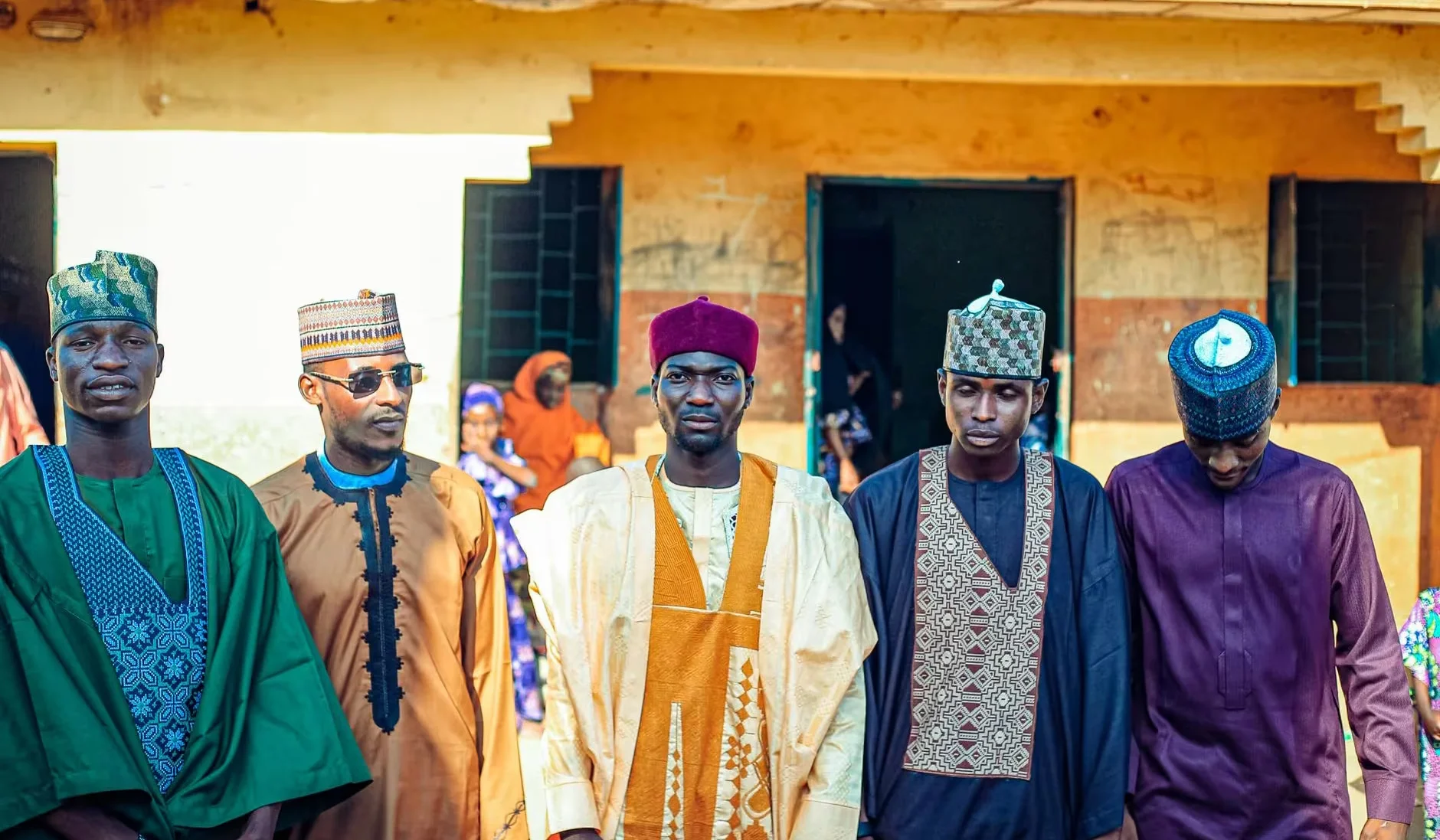 A group of men wearing traditional attire for a cultural gathering outdoors.