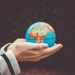 Person holding a small globe in hands, showcasing Earth. Ideal for global concepts or travel themes.