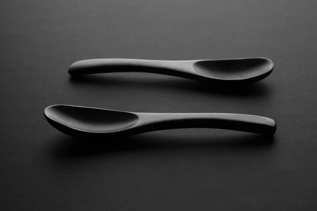 Artistic monochrome image of two wooden spoons on a dark surface, ideal for minimalist design.