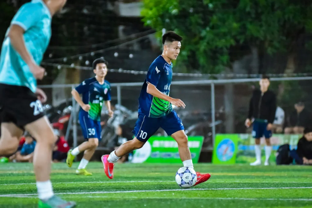 Dynamic action shot of a football player in full motion during a match in Hà Nội, Vietnam.