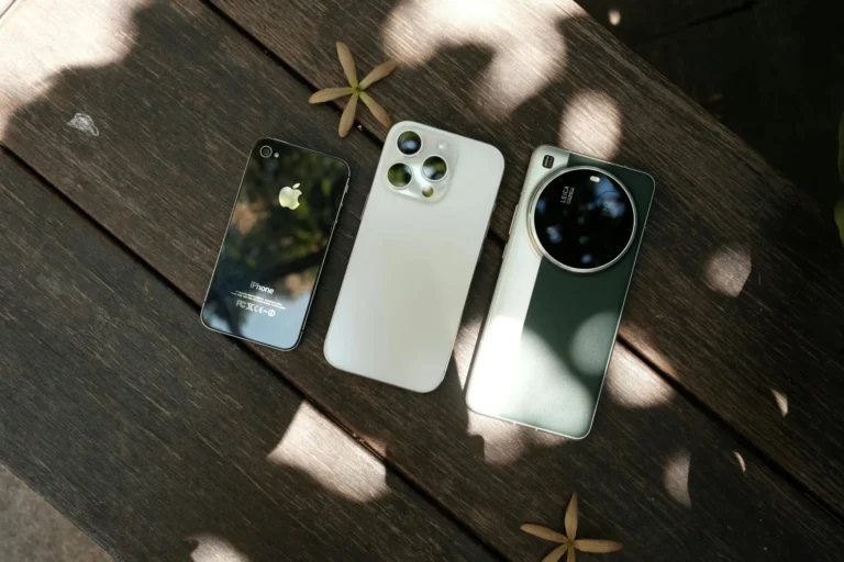 Three modern smartphones displayed on a wooden surface with natural lighting.