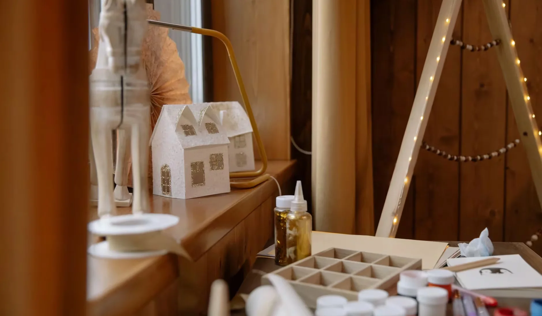 A warm and inviting arts and crafts station featuring Christmas decorations and materials on a wooden table.