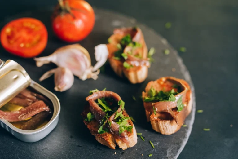 Mouth-watering bruschetta topped with anchovies and fresh herbs, paired with tomatoes and garlic.