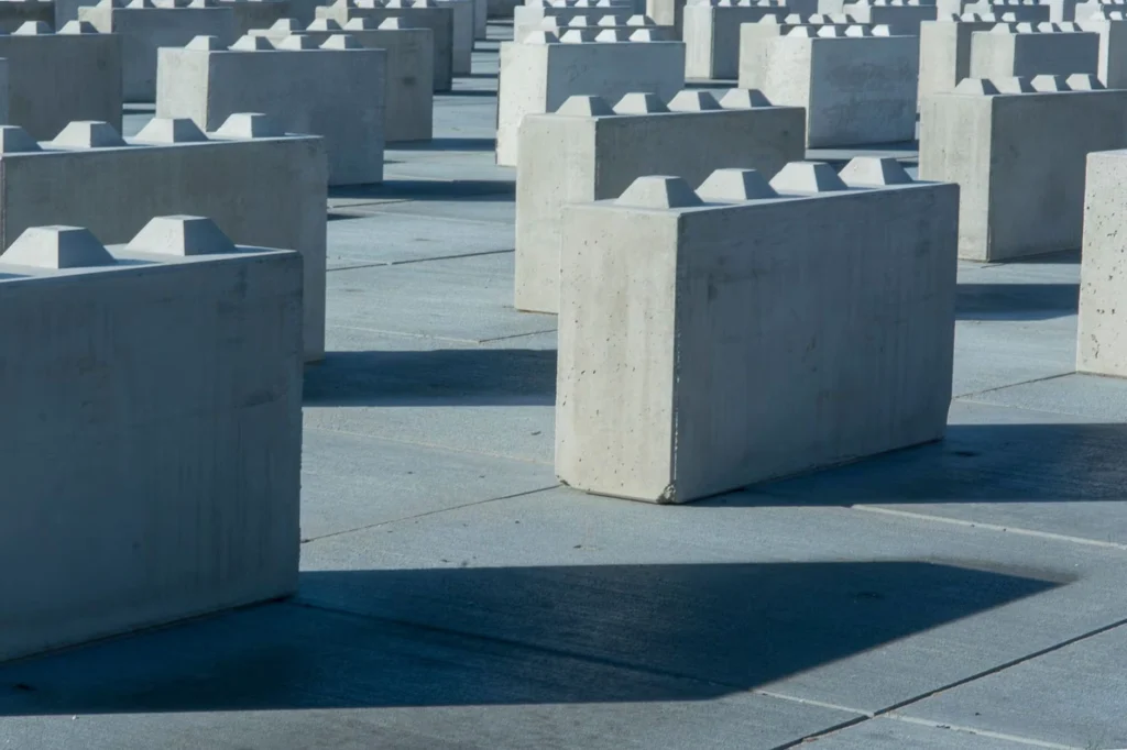Concrete blocks arranged in geometric pattern outdoors under sunlight casting long shadows.