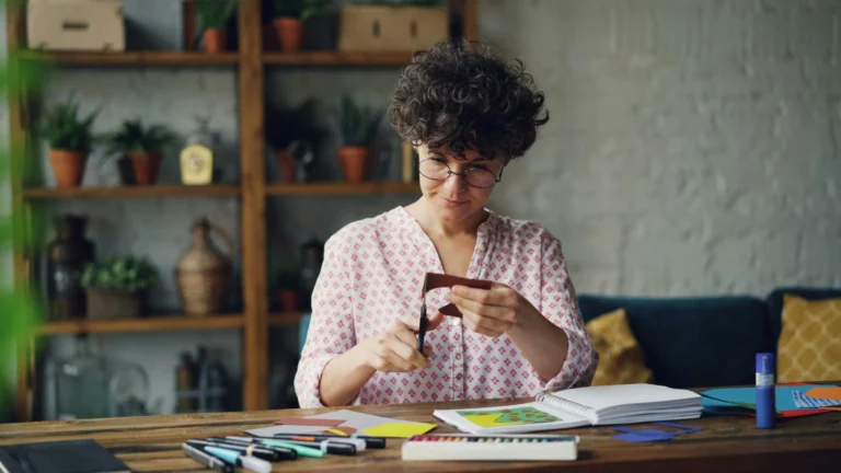 Woman engaged in crafting activities with paper and scissors in a cozy indoor setup.