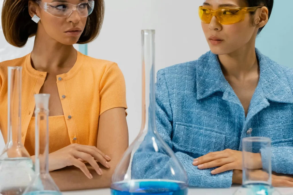 Two women wearing goggles in a lab setting, focusing on scientific research and experiments.