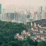 Urban skyline with densely packed skyscrapers and green foreground, depicting urban and natural elements.