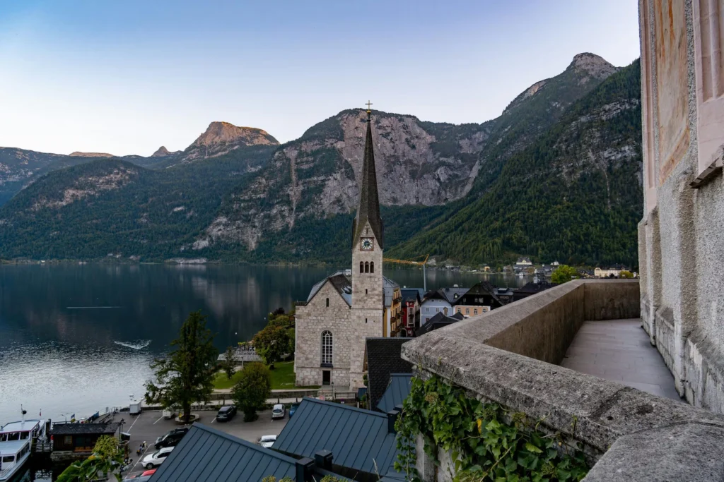 Serene view of Hallstatt village church and lake with mountain backdrop at dusk.