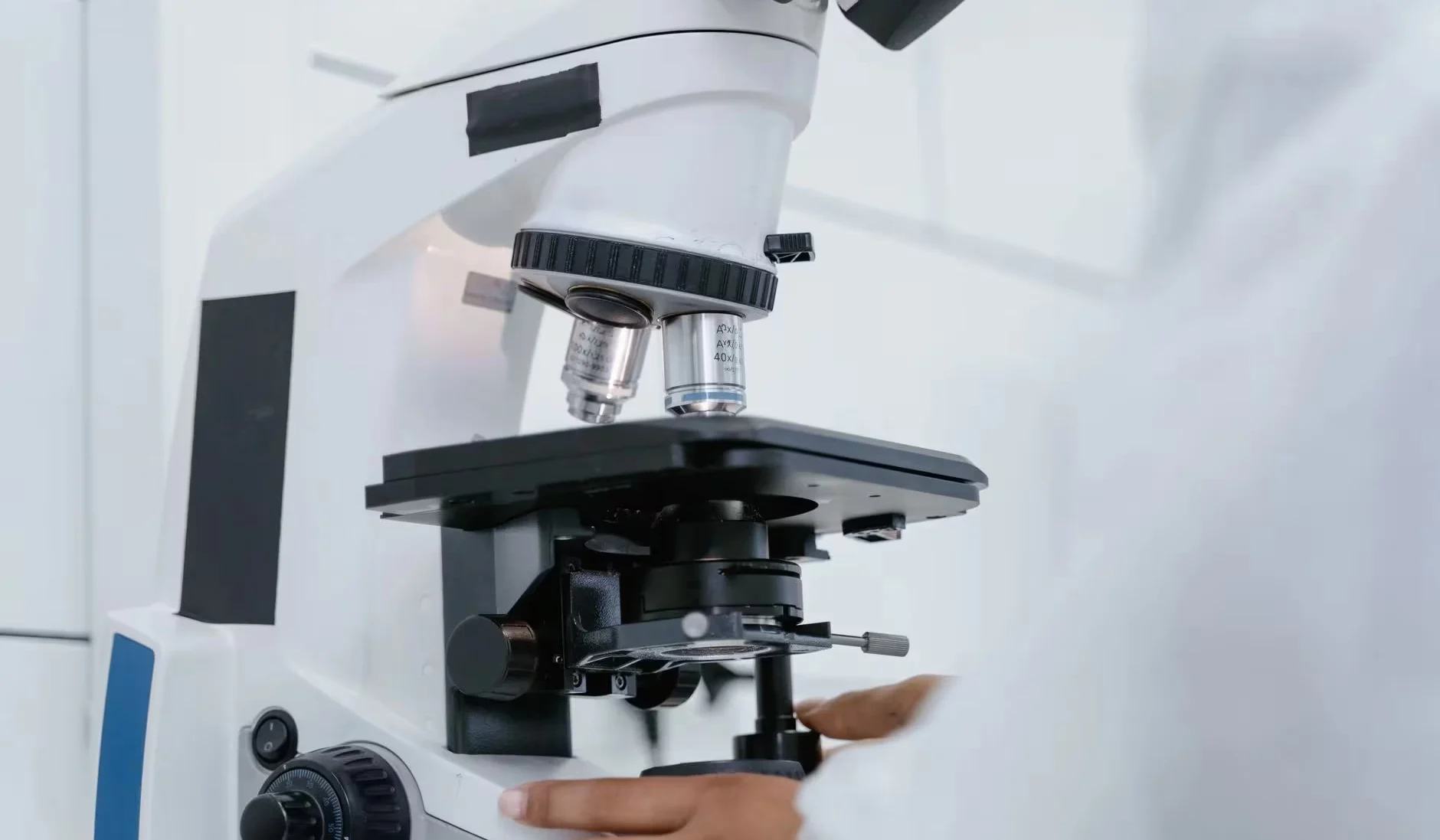 Detailed view of a scientist operating a microscope in a laboratory setting.
