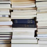 A collection of stacked books with visible Holy Bibles in a library arrangement.