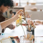 Children painting and drawing together in an art workshop, holding paintbrush and using colors.