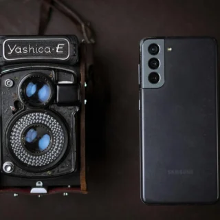 A vintage Yashica camera next to a modern smartphone, showcasing old and new technology.