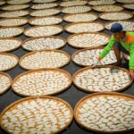 Man arranging fish crackers in a traditional setting in Indramayu, West Java, Indonesia.