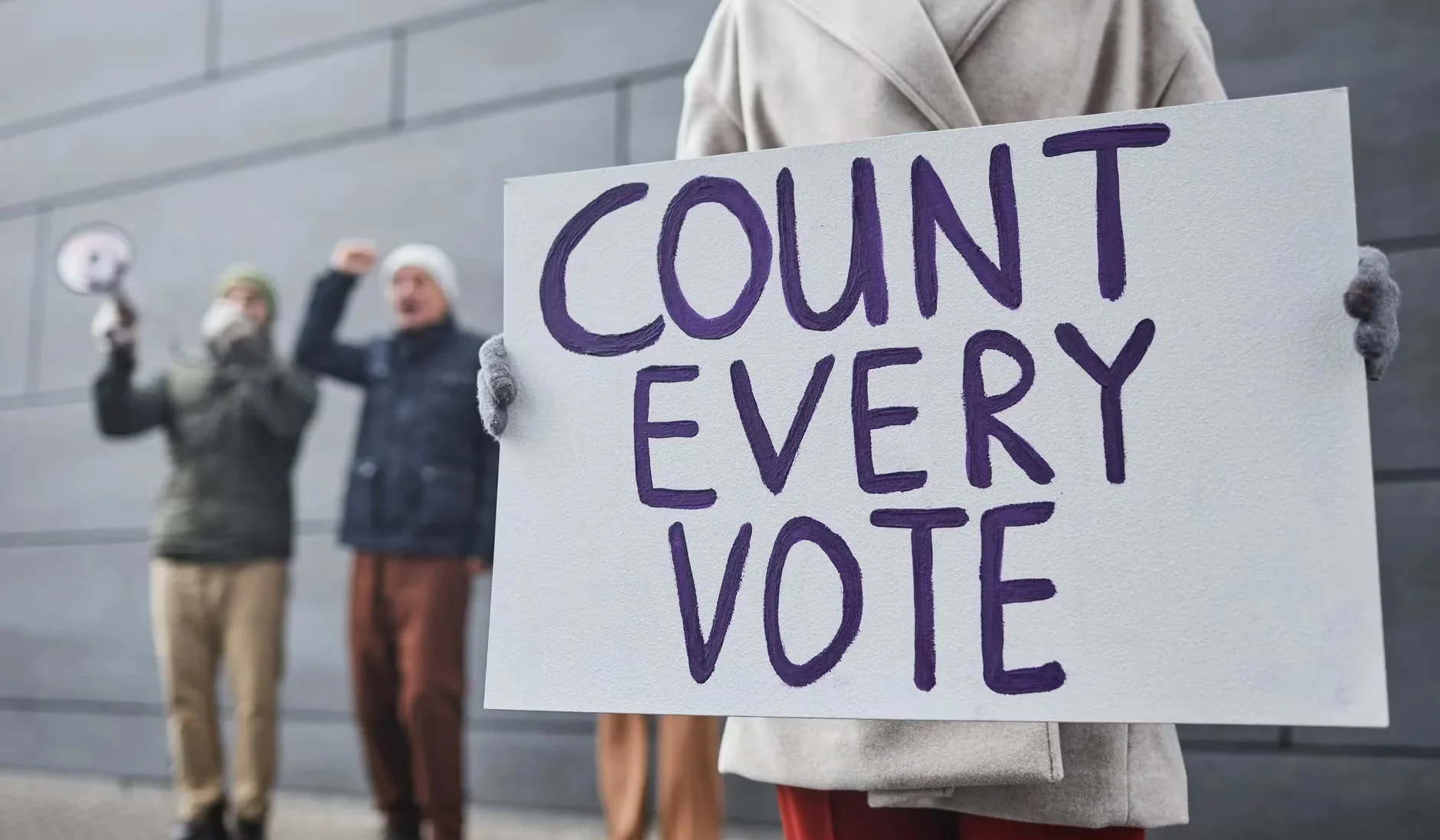 Protesters holding signs and chanting for fair vote count during a winter rally.